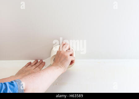 Renovierung der Wohnung - Vorbereitung der Wände zum Lackieren. Maler behebt Klebeband an der Wand vor dem Lackieren Stockfoto