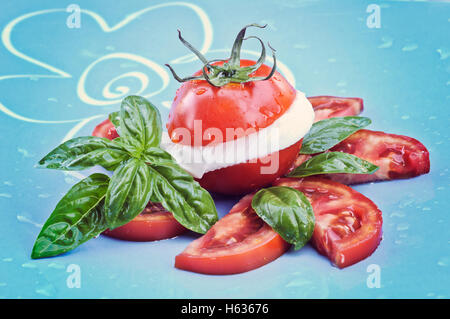 Tomate und Mozzarella mit Basilikum Blätter auf einem Teller Stockfoto