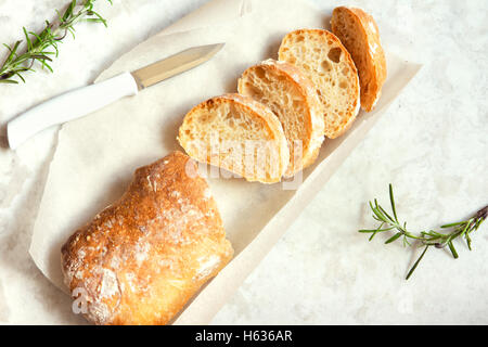 Italienisches Brot Ciabatta und Rosmarin auf weißem Marmor Hintergrund - frischem selbstgebackenem Brot Bäckerei Stockfoto