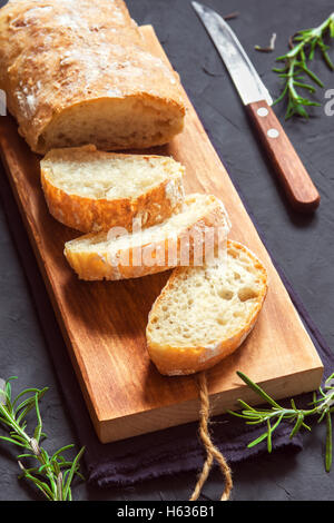 Italienisches Brot Ciabatta und Rosmarin auf schwarzem Hintergrund - frischem selbstgebackenem Brot Bäckerei Stockfoto