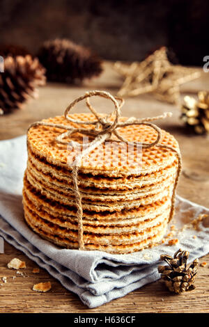 Stapel von traditionellen niederländischen Karamel Waffeln mit Jute Garn auf rustikalen hölzernen Hintergrund mit Weihnachts-Dekor - hausgemachte C gefesselt Stockfoto