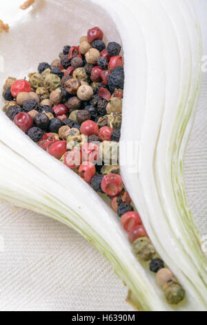 Bunte Pfefferkörner in eine weiße Zwiebel. Waagerechten Schnitt mit weißem Hintergrund. Stockfoto