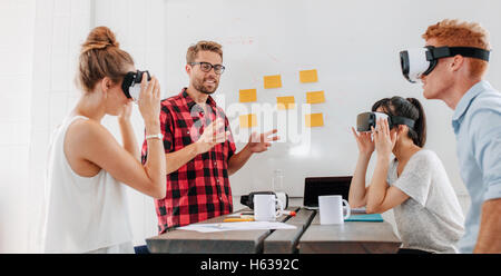 Geschäftsleute, die mit virtual Reality Brille während der Sitzung. Team von Entwicklern, virtual-Reality-Kopfhörer Tests und diskutieren Stockfoto
