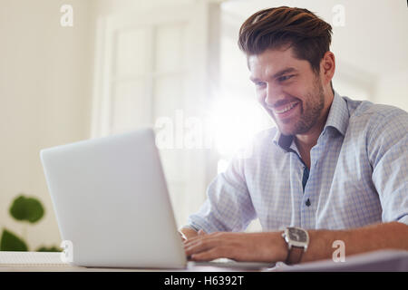 Schuss von glücklicher junge Mann am Tisch sitzen und arbeiten am Laptop-Computer. Geschäftsmann, vom home-Office arbeiten. Stockfoto
