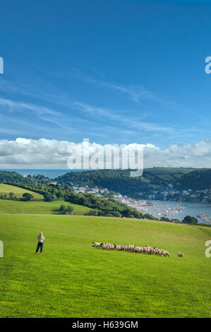 Frau und Herde von Schafen mit Blick auf den berühmten Hafen von Dartmouth in Devon, Großbritannien an einem Sommertag mit schönen fernen Wolken Stockfoto