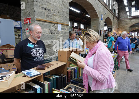 Frau Wahl einen gebrauchten Buch auf einem im Samstag Antiquitäten Marktstand in der tavistock Pannier Market, dartmoor, Devon Stockfoto