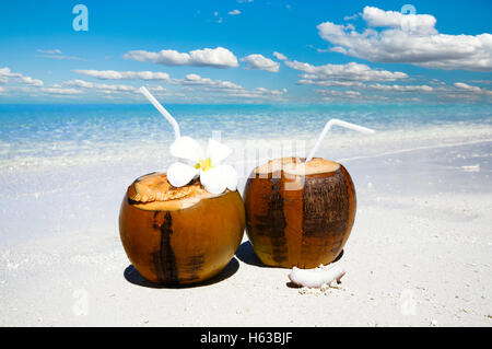 Zwei Kokosnuss Cocktails am weißen Sandstrand neben sauberen Meerwasser. Urlaub und Reisen-Konzept Stockfoto