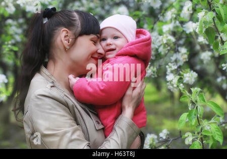 Park-Mutter mit Zwillingen auf Plaid im Freien im Apfelgarten Stockfoto