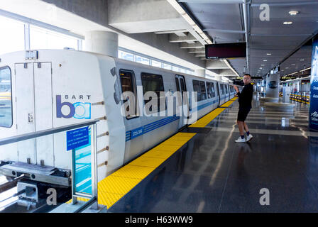 San Francisco, CA, USA, Chinese man steht allein im leeren Zug BART Subway Metro Station Platform am Flughafen, pendeln Züge Stockfoto