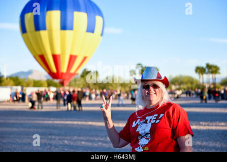 Eine Frau hält ein Friedenszeichen Handbewegung nach der Abstimmung früh in Nevada mit einem Heißluftballon im Hintergrund Stockfoto