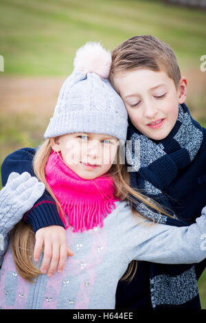 Bruder und Schwester posiert im Freien im Herbst tragen Wurm Kleidung und Gefühl glücklich zusammen Stockfoto