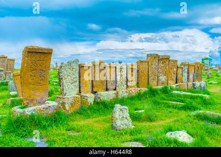 Die Reihe der alten Khachkars, ruiniert durch Verwitterung und mit Moos und Flechten bedeckt steht auf der grünen Wiese Noratus Friedhof, Stockfoto