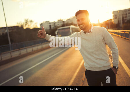 Mann ein Taxi hagelt, während die Sonne untergeht Stockfoto