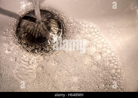 Fließendem Wasser gießt in ein Waschbecken mit modernen Edelstahl-Spüle Stecker Montage Stockfoto