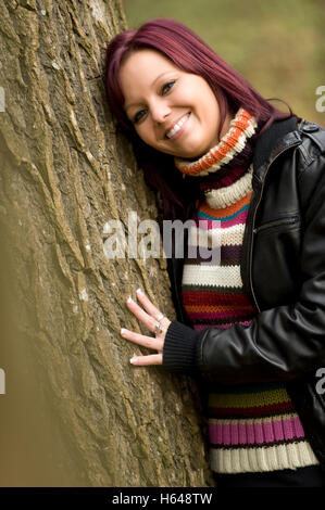 Junge Frau lehnte sich gegen einen Baum Stockfoto