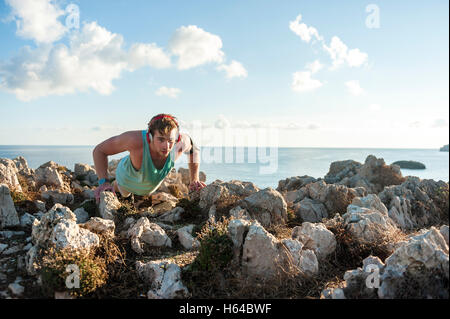 Spanien, Mallorca, Sportler auf felsigen Küste am Morgen stehen Pushup Stockfoto