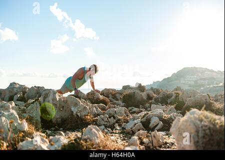 Spanien, Mallorca, Sportler auf felsigen Küste am Morgen stehen Pushup Stockfoto