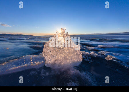 Sonne bei Sonnenuntergang leuchten durch die transparente Textur von der Eisscholle im Baikalsee. Stockfoto