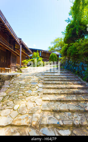 Eingelegten Steinstraße neben traditionellen Holzhäusern im japanischen Stil in Tsumango Dorf auf der historischen Route der Nakasendo in Japan Stockfoto