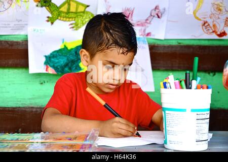 Kleiner Junge am Tisch schreiben und Kunst zu machen. Stockfoto