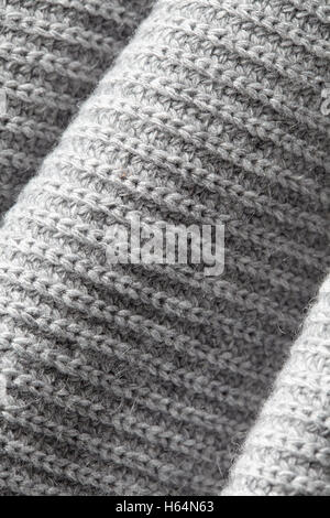 Fragment eines faltigen gestrickten grauen Tuchgewebe als eine Hintergrundtextur Stockfoto