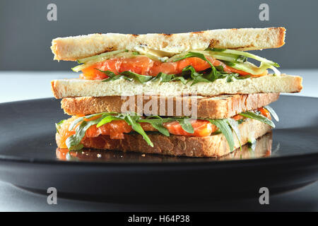 Geräucherter Lachs Sandwich auf Roggen mit Rucola, Frischkäse auf dem Teller Stockfoto