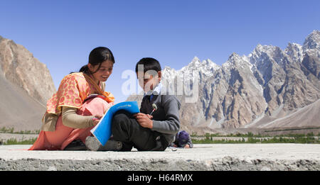 Lehrer helfen Studenten studieren auf Dach der Schule befindet sich im Karakorum-Gebirge in Passu, Nordpakistan Stockfoto
