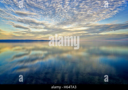 Sonnenuntergang Wolken spiegeln sich in einer sehr ruhigen Meer Stockfoto