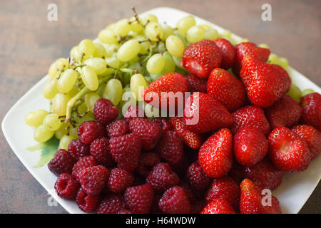 Platte mit Mischung aus Erdbeeren, Himbeeren und Trauben, Draufsicht closeup Stockfoto
