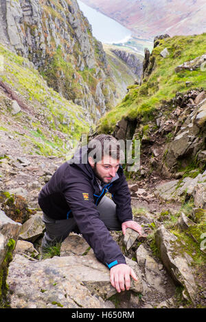 Männliche in Mittzwanziger kriechen, an Herrn ist Rake auf Scafell, Seenplatte, während eine Paramo-Jacke zu tragen Stockfoto