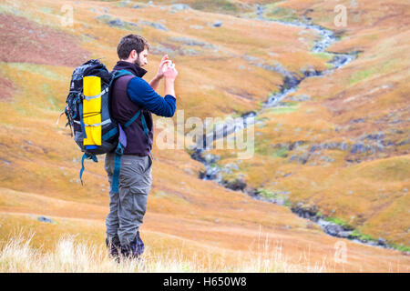 Mann in seiner Mitte der zwanziger Jahre wandern im Lake District, ein Foto mit einem Smartphone Stockfoto