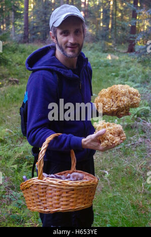 glücklicher Mann mit einem Korb hält in einer Hand Pilz Stockfoto