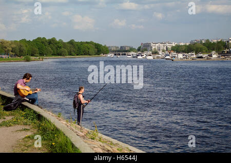 Sankt Petersburg, Russland - 21. Mai 2014: Gitarist und einen Fishermansitting - Stand am Fluss Niva an sonnigen Tag Stockfoto
