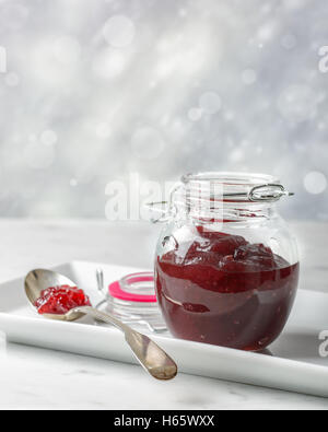 Cranberry-Sauce im Glas auf eine weiße Schale mit Löffel Stockfoto