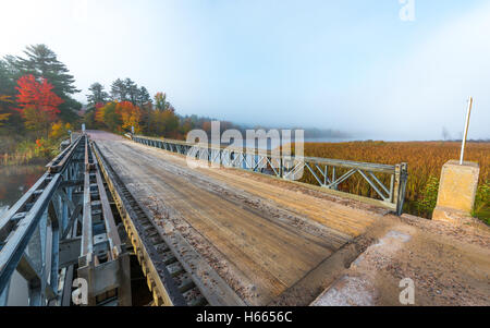 Oktober Morgensonne bescheint eine einspurige Stahl und Holz Brücke über Corry See. Stockfoto