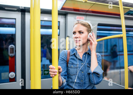 Schöne junge Frau mit Kopfhörern in u-Bahn Zug Stockfoto