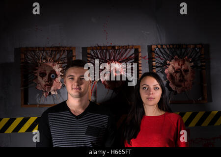 Junger Mann und Frau vor dunkelhäutigen Gesichtern für scary Halloween Thema Terror Tatort Stockfoto