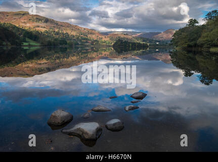 Helm, Felsen und Wolken spiegeln sich in Grasmere See, Herbst, Nationalpark Lake District, Cumbria, UK Stockfoto