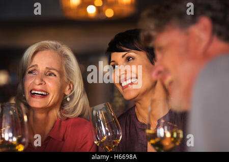Lächelnde Frauen trinken weiß bei Weinbar Stockfoto