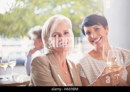 Porträt, Lächeln, Mutter und Tochter Toasten Weißweingläser im sonnigen restaurant Stockfoto