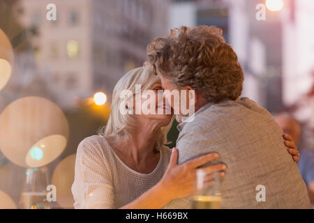 Liebevolle älteres Paar küssen in städtischen Straßencafé Stockfoto