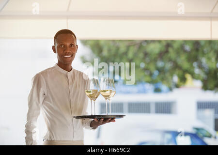 Porträt, Lächeln Kellner servieren weißen Wein auf Tablett im restaurant Stockfoto
