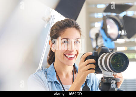 Lächelnde Fotografin hinter Kamera im studio Stockfoto