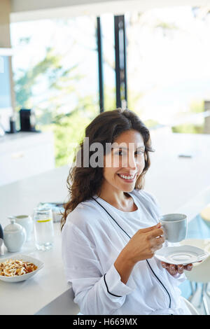 Lächelnde Frau Porträt im Bademantel Kaffeetrinken in Morgen Küche Stockfoto