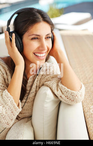 Lächelnde Frau Musikhören mit Kopfhörer auf sofa Stockfoto