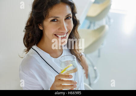 Lächelnde Frau Porträt im Bademantel Trinkwasser mit Zitrone Stockfoto