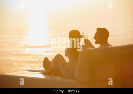 Silhouette paar Weingläser auf Liegestuhl mit Blick auf den Sonnenuntergang Ozean Toasten Stockfoto