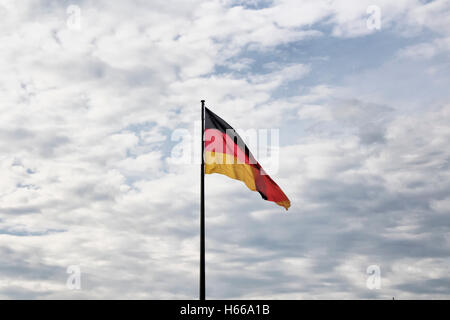 Deutsche Flagge Wellen mit bewölktem Himmelshintergrund vor dem Reichstagsgebäude in Berlin. Stockfoto