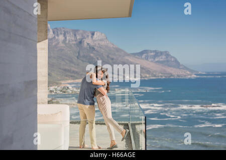 Paar, umarmen, auf sonnigen Luxus Balkon mit Meer und Bergblick Stockfoto