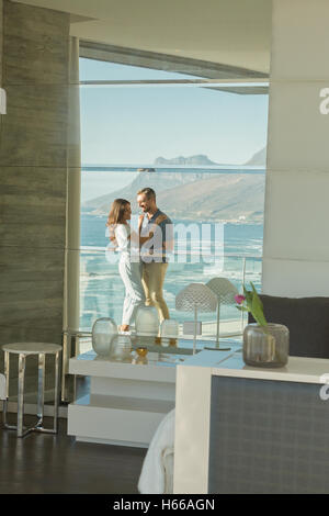 Reflexion der paar umarmt auf Luxus Balkon mit Sonne Meer und Bergblick Stockfoto
